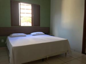 a bedroom with a white bed with a window at Hotel Meri in Conselheiro Lafaiete