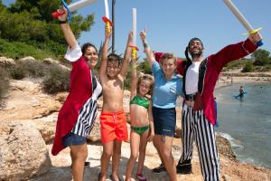 un grupo de personas de pie en una playa con las manos en el aire en RVHotels Hotel Ametlla Mar en L'Ametlla de Mar