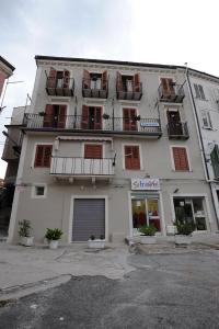 - un grand bâtiment blanc avec des fenêtres et des balcons dans l'établissement Pensione Oliva, à Lagonegro