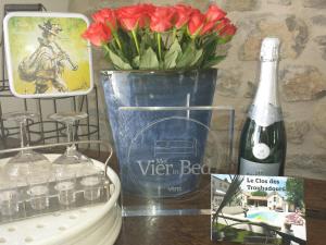 een fles wijn en een vaas met rode bloemen bij Le Clos des Troubadours in Pennautier