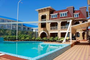 a swimming pool in front of a building with a house at Marseille Resort in Zatoka