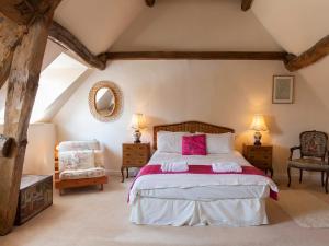 a bedroom with a large bed and two chairs at Pilgrim Cottage in Bourton on the Hill