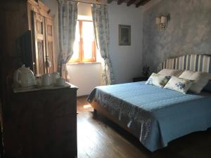 a bedroom with a blue bed and a window at Il Podere Bellavista in Montecatini Val di Cecina