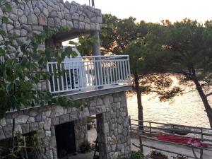 a balcony on a stone building next to the water at Apartments Pomeštak in Pomena