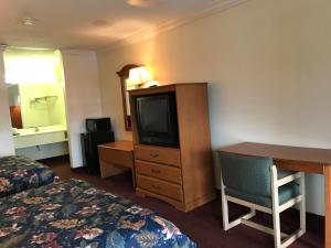 a hotel room with a bed and a desk and a television at Bayfront Inn Biloxi in Biloxi