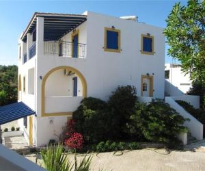 ein weißes Haus mit blauen Fenstern und Pflanzen in der Unterkunft Petros Studios Kythera in Kýthira