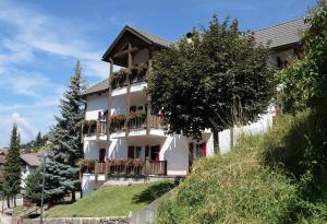 a white building with balconies on a hill at Apartments Casa Metz in Santa Cristina Gherdëina