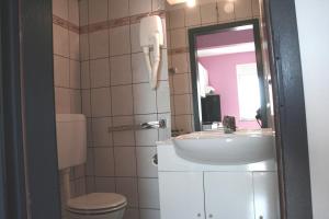 a bathroom with a sink and a toilet and a mirror at Apartments Jann in Krk