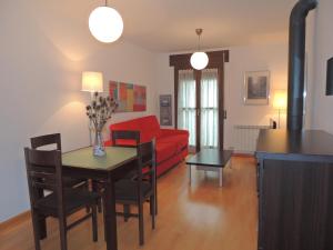a living room with a table and a red couch at Apartamento céntrico con WIFI en Biescas in Biescas