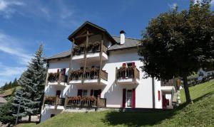 a large white building with balconies and flowers at Apartments Casa Metz in Santa Cristina in Val Gardena