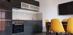a kitchen with yellow chairs and a table and a tv at Apartmani Ortolio in Viganj