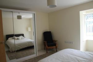 スランバイルベハンにあるBright modern house beside Snowdoniaの鏡付きのベッドルーム(ベッド1台、椅子付)