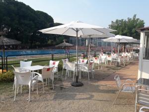 a row of tables and chairs with white umbrellas at Càmping Vila Village in Sant Feliu de Buixalleu