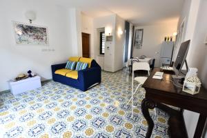 Una sala de estar con un sofá azul y un escritorio. en Il Gelsomino Amalfi, en Amalfi