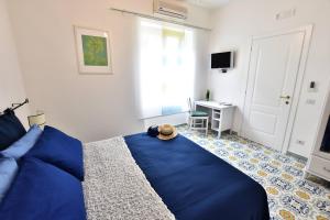 Un dormitorio con una cama azul y un escritorio. en Il Gelsomino Amalfi, en Amalfi