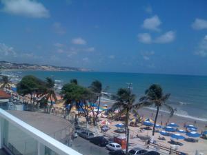 vistas a una playa con palmeras y sombrillas en Don Limpone Apart Hotel, en Natal