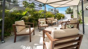 une terrasse avec des chaises, des tables et un parasol dans l'établissement Villa RG Boutique Hotel - Adults Only, à Playa del Ingles