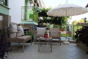 een patio met 2 stoelen, een tafel en een parasol bij Maria & Kyros House in Parga