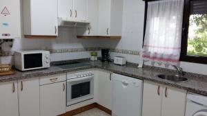 ヌエバ・デ・リャネスにあるChalet "El Bosque" 5 habitacionesの白いキャビネット、シンク、電子レンジ付きのキッチンが備わります。