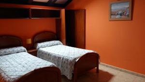 two beds in a room with orange walls at Chalet "El Bosque" 5 habitaciones in Nueva de Llanes