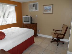 a bedroom with a bed and a chair and a tv at Bayside Inn and Marina in St Pete Beach