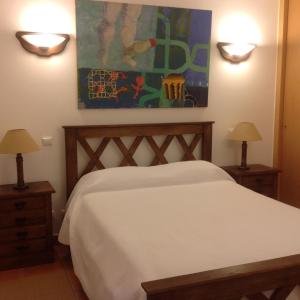 a bedroom with a bed with two lamps and a painting at Férias Lagos in Lagos