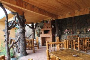 a restaurant with wooden tables and chairs and a stone wall at Villa Edemi in Tsqaltubo