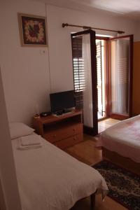 1 dormitorio con 2 camas y escritorio con TV en Villa Lina, en Ičići