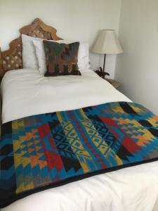 a bed with a colorful blanket on top of it at Taos Goji Farm & Eco-Lodge Retreat in Arroyo Seco