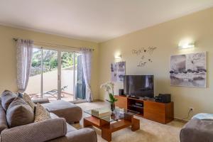 a living room with a couch and a tv at Sunny Ponta "Nomads' village" in Ponta do Sol