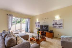 a living room with a couch and a tv at Sunny Ponta "Nomads' village" in Ponta do Sol