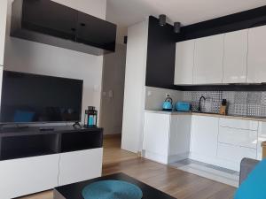 a kitchen with white and black cabinets and a table at Margaret Apartments in Kraków