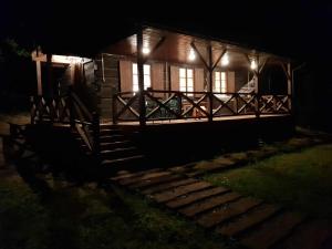 uma cabana de madeira à noite com luzes no alpendre em Nad Lipcykiem em Nowy Gaj