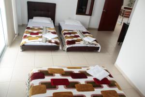 two beds sitting on a tiled floor in a room at Hotel Santorini Neiva in Neiva +11 photos