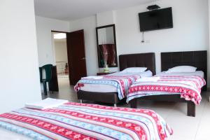 a bedroom with two beds and a flat screen tv at Hotel Santorini Neiva in Neiva