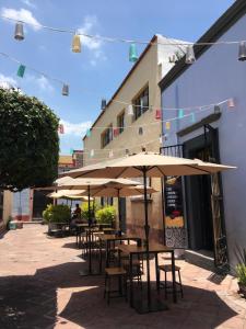 una fila de mesas y sillas con sombrillas fuera de un edificio en El Petate Hostel, en Querétaro