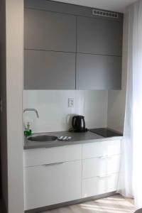uma cozinha com armários brancos e um lavatório em Apartman Kyjev em Podhájska