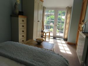 a bedroom with a bed and a table and a window at Garth Engan Private Self Contained B&B with Garden Area in Llanbedr