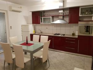 cocina con mesa de cristal y sillas blancas en Apartment Lava, en Kaštela