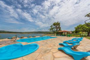 a pool with blue lounge chairs next to a body of water at Pousada Solar Dona Dora in Capitólio