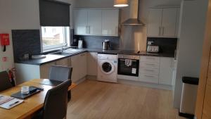 a kitchen with white cabinets and a table and a washer at Newtown Apartments in Boʼness