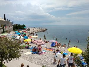 een menigte mensen op een strand met parasols bij Seafoam Apartment in Rijeka
