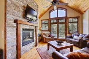 a living room with a stone fireplace and a tv at Slopeside Villa 126 Next To WP Resort I Steam Shower I Great Views I Private Hot Tub I Activity Program in Winter Park