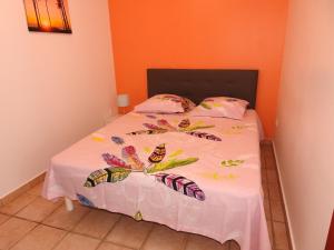 a bed with a white bedspread with butterflies on it at gîte CITRONNELLE in Bouillante