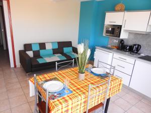 eine Küche und ein Wohnzimmer mit einem Tisch und einem Sofa in der Unterkunft gîte CITRONNELLE in Bouillante