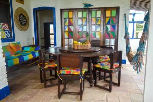 a dining room with a table and chairs and a room with stained glass at Hostel Ave Rara in Praia do Frances