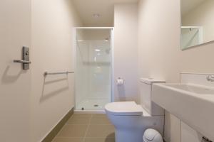 a white bathroom with a toilet and a shower at Otago Village in Dunedin +34 photos