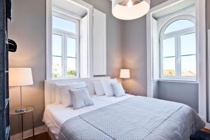 a bedroom with a white bed with two windows at Saboia Terrace 515 by Saboia Collection in Monte Estoril