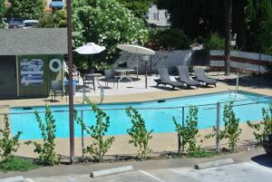una piscina con sillas, sombrillas, mesa y sillas en Vino Inn & Suites, en Atascadero