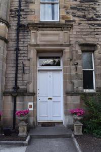 a white door on a stone building with flowers at Ardgowan Guest House in Edinburgh